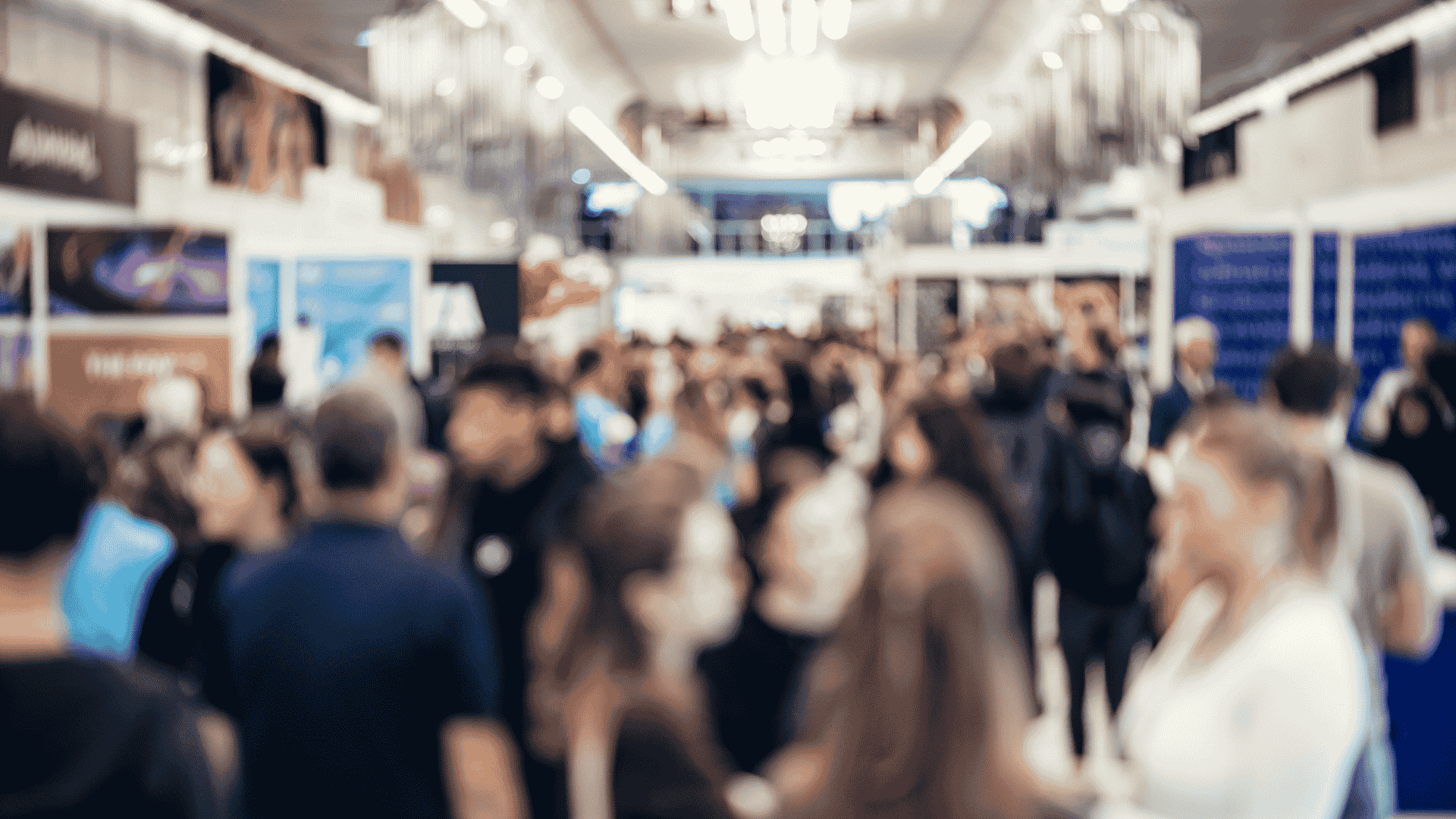 Público caminhando por um corredor de feira de tecnologia, com estandes nas laterais e ambiente movimentado, representando networking e inovação em eventos de tecnologia de 2026.